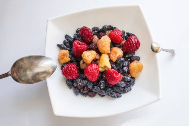 Hafif bir arka planda tatlılı bir tabak, farklı boyutlarda iki kaşığın yanında. Eşit fırsatlar, ilk avantaj, ek kaynak.