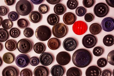 Giysiler için koyu renk düğme arkaplanda kırmızı bir düğme. Parlak bireysellik, farklılık, ayırt edici özellik. Yukarıdan görüntüle.