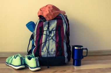 Kampanya için her şey toplandı. Yerde bir sırt çantası, bir termo bardak, spor ayakkabıları, bir battaniye var. Yeni bir yolculuk, bir yürüyüş, keşfedilmemiş bir rota. Renk tonu.