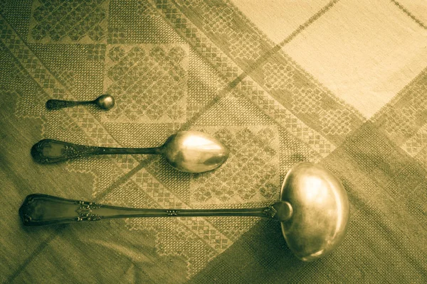 Çatal bıçak takımı, eski bir masa örtüsü üzerinde antika gümüş. Ev, yemek pişirme, eski aletler, mutfak. Retro sitel, vignetting, üst görünüm.