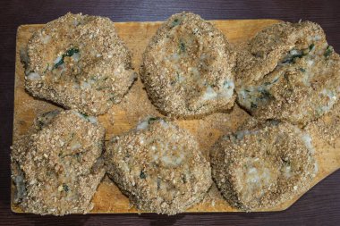 Eski tahta üzerinde altı tane el yapımı pirzola var. Etrafına ekmek kırıntıları serpiştirilmiş. Ev yemeği, aşçılık becerileri. Yukarıdan görüntüle.