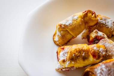 Kahvaltı, beyaz tabakta reçelli kruvasan. Evde yemek pişirmek, basit bir tarif. Yan ışıklandırma, kopyalama alanı.