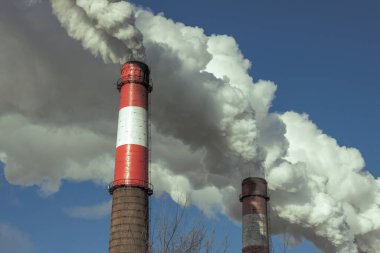 Küresel ısınma, atmosferik emisyonlar. Mavi gökyüzüne karşı beyaz duman bulutları. Yanal güneş ışığı.