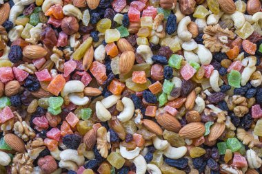 Kurumuş tropikal meyve parçalarının parlak, renkli arka planı ve çeşitli ceviz çeşitleri. Besleyici atıştırmalıklar, protein kaynağı. Gün ışığı.