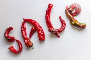 Acı biberden yapılmış parlak kırmızı harfler. Acil satış, iyi bir teklif, indirimler. Işık arkaplan, üst görünüm.