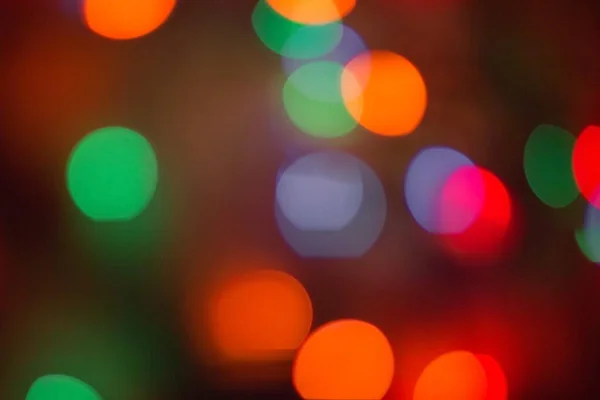 Bright, colored background. Everything is blurry, abstraction. Festive, night lighting. Red, orange, blue and green tones.