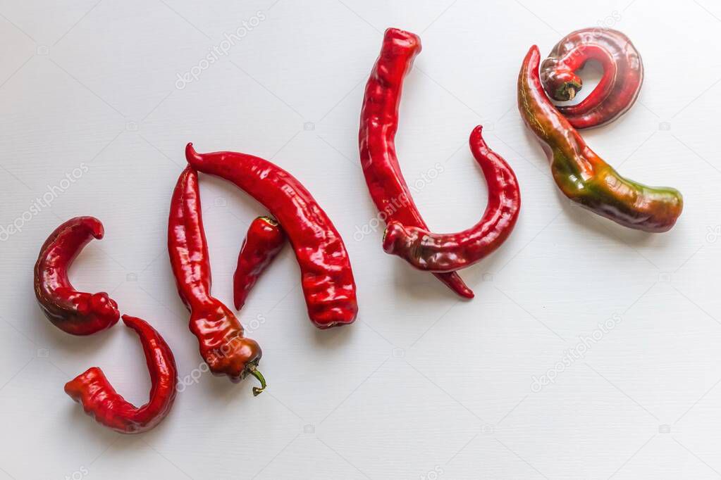 Bright red letters made from hot pepper. Urgent sale, hot offer, discounts. Light background, top view.