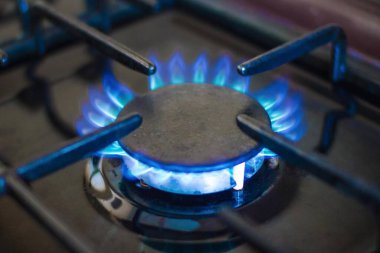 Evde sıcak yemek pişirmek, gaz ocağı. Siyah arka plandaki mavi alev, kenarları bulanık..