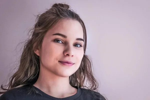 The face of a smiling young girl. Long blond hair, green eyes, black T-shirt. Modern youth, a teenager. Daylight, copy space.