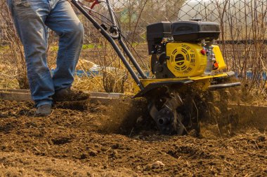 Toprağı sabanla sürmek, bahçedeki bahar işleri, çiftçilik, ekme. Kahverengi toprak pulluğun altından uçar. Gün ışığı.