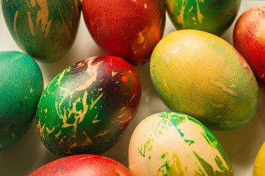 Çok renkli, parlak yumurtalar. Kırmızı, sarı, yeşil gölgeler, soyutlama. Üst görünüm, ışık arkaplan, tabak.