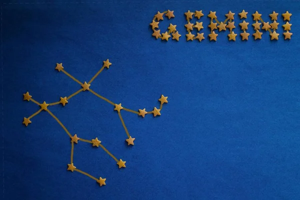 Constellation Gemini, a horoscope for born in June. The inscription and constellation are made up of small decorative stars. Blue background, copy space. Figure made by the author.