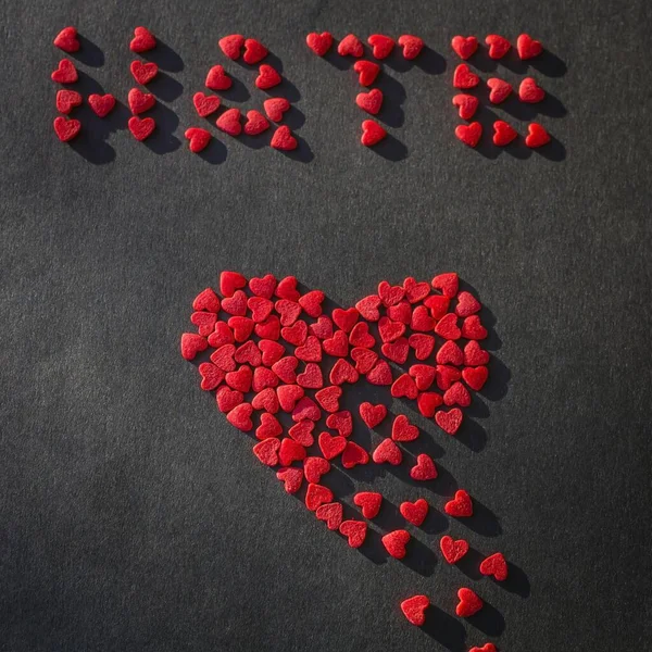 Red heart breaks into pieces, broken. Top inscription Hate. Dark background. Concept.  View from above.