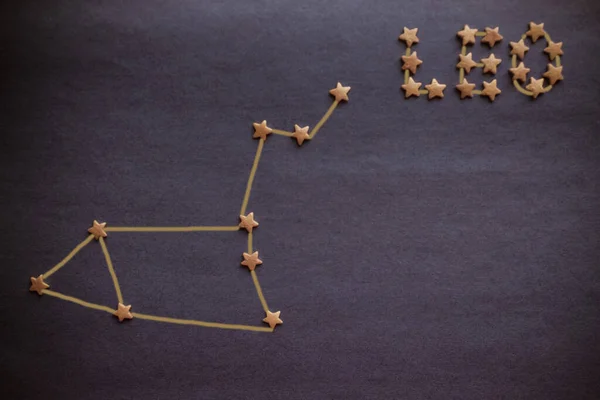 Yellow stars, the scheme of the constellation of the Lion on a lilac background. Astrology, the sign of the zodiac. View from above. The picture is made by the author.