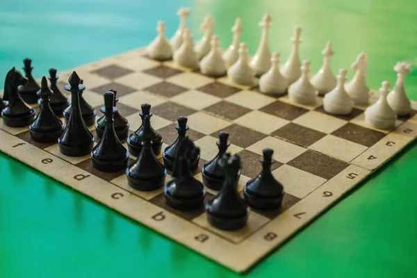 A game of chess, the initial stage, the blacks are waiting for the first step of the whites. Confrontation, alignment of forces. Daylight, the background is blurred.
