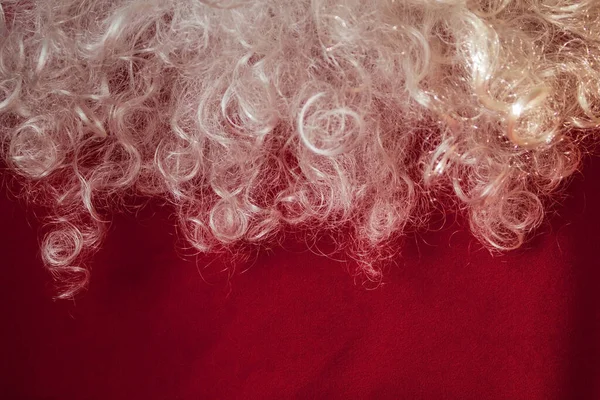 新年的背景 白色卷曲的圣诞老人的胡子在明亮的红色背景 恭喜你的节日 盼望已久的礼物 — 图库照片