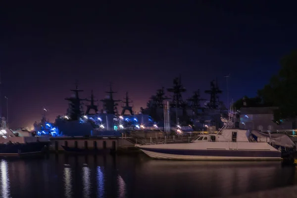 港での軍艦 濃い青 紫の空 手前は小舟 — ストック写真