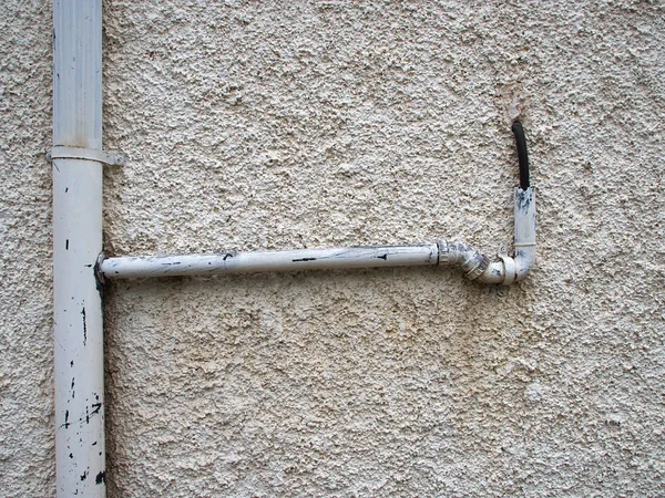 Tubería de drenaje de metal contra una pared blanca —  Fotos de Stock