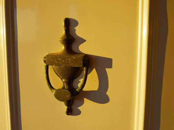 Golpeador de metal oxidado en una puerta amarilla —  Fotos de Stock
