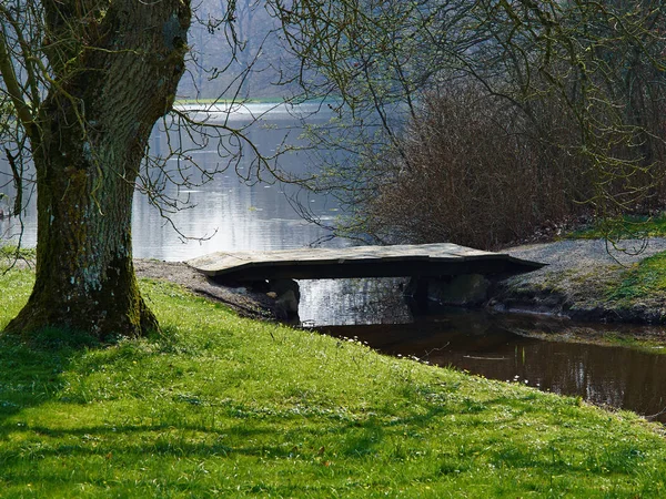 Pequeño puente de pie de madera sobre el agua de un lago — Foto de Stock