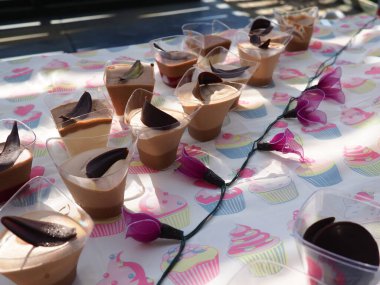 Açık hava bahçe doğum günü partisinde porsiyon bardaklarda servis edilen üç çeşit çikolatadan yapılmış mus.