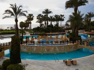 Yüzme havuzu, palmiye ağaçları ve Kıbrıs tatil beldesi Paphos 'un güneşlik yatakları - büyük ve popüler yaz tatili beldesi - Elysium Hotel, Paphos, Kıbrıs, Temmuz 2019