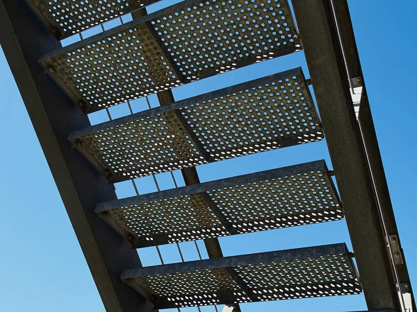 Metal stairs staircase made with small round holes for emergency entry exit with clear blue sky background