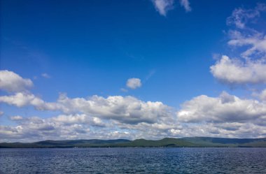 Deniz ve mavi gökyüzü. Göl üzerinde beyaz bulutlar. Yaz manzara
