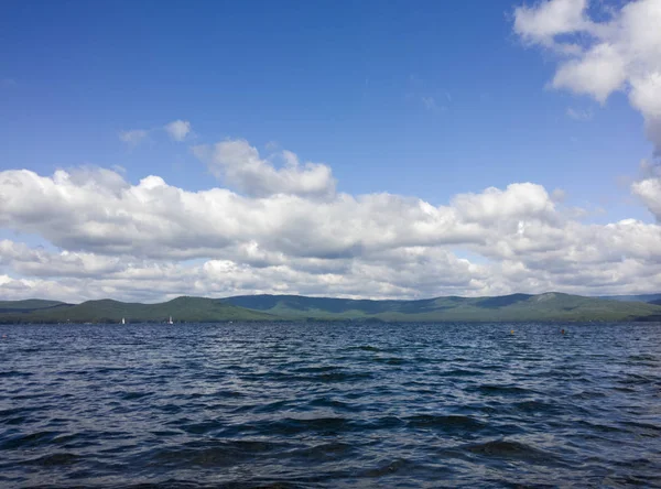 Deniz ve mavi gökyüzü. Göl üzerinde beyaz bulutlar. Yaz manzara