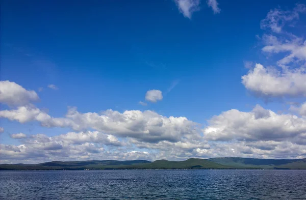 Deniz ve mavi gökyüzü. Göl üzerinde beyaz bulutlar. Yaz manzara