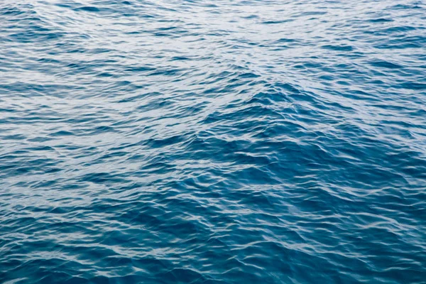 Clear water texture in blue. Background of the ocean and the sea backlit by the sun. — ストック写真