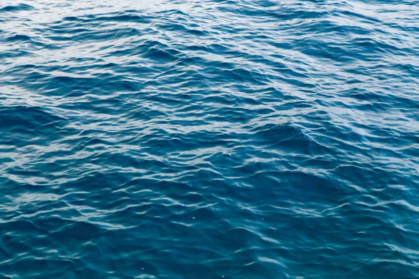 Textura de água clara em azul. Fundo do oceano e do mar retroiluminado pelo sol . — Fotografia de Stock