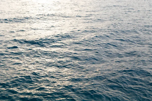 Textura de agua clara en azul. Fondo del océano y el mar retroiluminado por el sol . —  Fotos de Stock