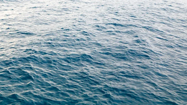 Textura de agua clara en azul. Fondo del océano y el mar retroiluminado por el sol . —  Fotos de Stock