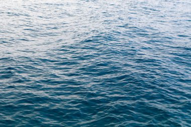 Mavili temiz su dokusu. Okyanusun ve denizin arkaplanı güneşle aydınlanıyor..