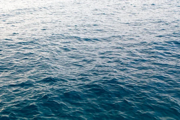 Textura de água clara em azul. Fundo do oceano e do mar retroiluminado pelo sol . — Fotografia de Stock