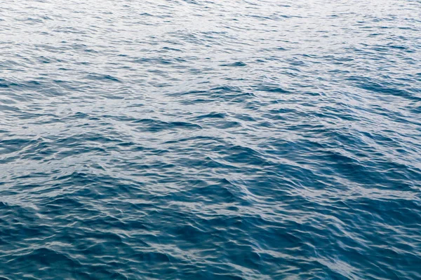 Clear water texture in blue. Background of the ocean and the sea backlit by the sun. — ストック写真