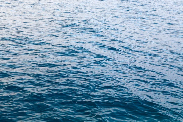 Textura de água clara em azul. Fundo do oceano e do mar retroiluminado pelo sol . — Fotografia de Stock