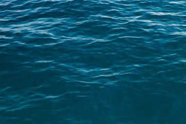 Mavili temiz su dokusu. Okyanusun ve denizin arkaplanı güneşle aydınlanıyor..