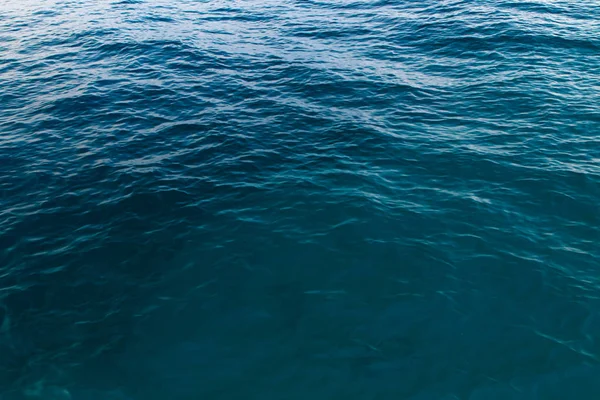 Textura de agua clara en azul. Fondo del océano y el mar retroiluminado por el sol . —  Fotos de Stock