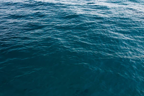 Textura de água clara em azul. Fundo do oceano e do mar retroiluminado pelo sol . — Fotografia de Stock