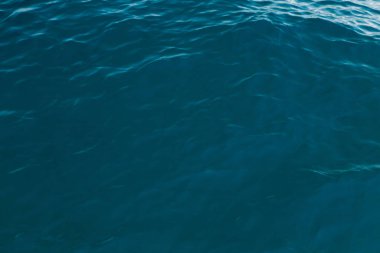 Mavili temiz su dokusu. Okyanusun ve denizin arkaplanı güneşle aydınlanıyor..