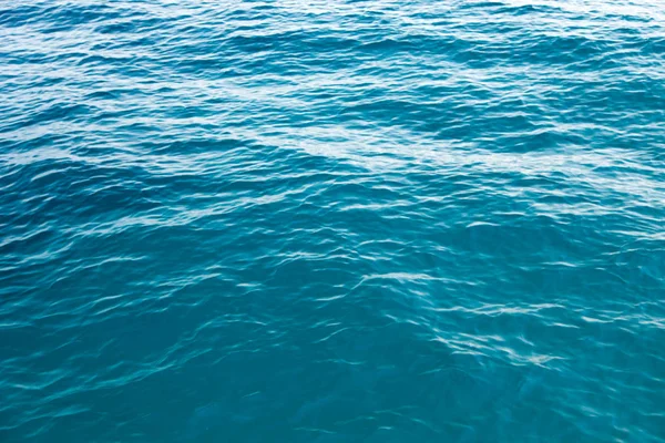 Textura de água clara em azul. Fundo do oceano e do mar retroiluminado pelo sol . — Fotografia de Stock