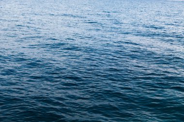 Mavili temiz su dokusu. Okyanusun ve denizin arkaplanı güneşle aydınlanıyor..