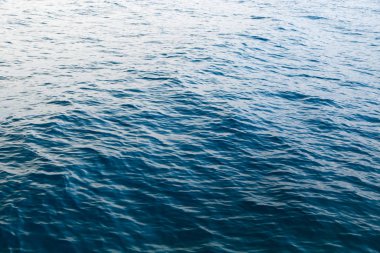 Mavili temiz su dokusu. Okyanusun ve denizin arkaplanı güneşle aydınlanıyor..