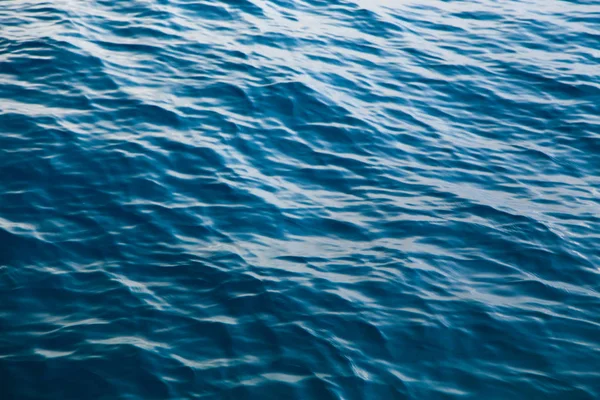 Textura de água clara em azul. Fundo do oceano e do mar retroiluminado pelo sol . — Fotografia de Stock