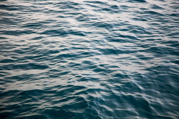 Clear water texture in blue. Background of the ocean and the sea backlit by the sun. — Stockfoto