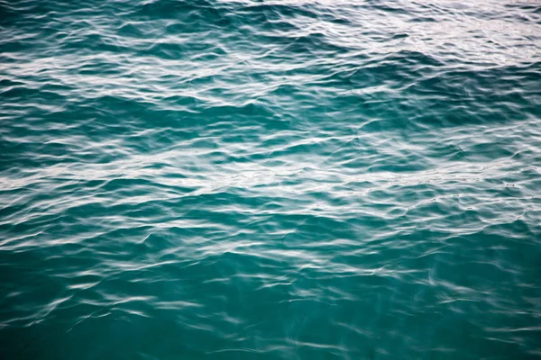 Textura de agua clara en azul. Fondo del océano y el mar retroiluminado por el sol . — Foto de Stock