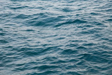 Mavili temiz su dokusu. Okyanusun ve denizin arkaplanı güneşle aydınlanıyor..