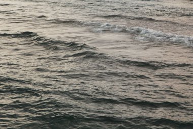 Mavili temiz su dokusu. Okyanusun ve denizin arkaplanı güneşle aydınlanıyor..